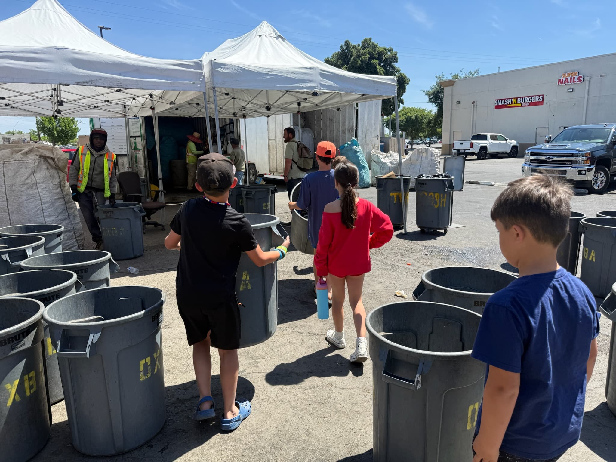 Students hauling bins at a recycling buy-back center during a Learn to Earn trip