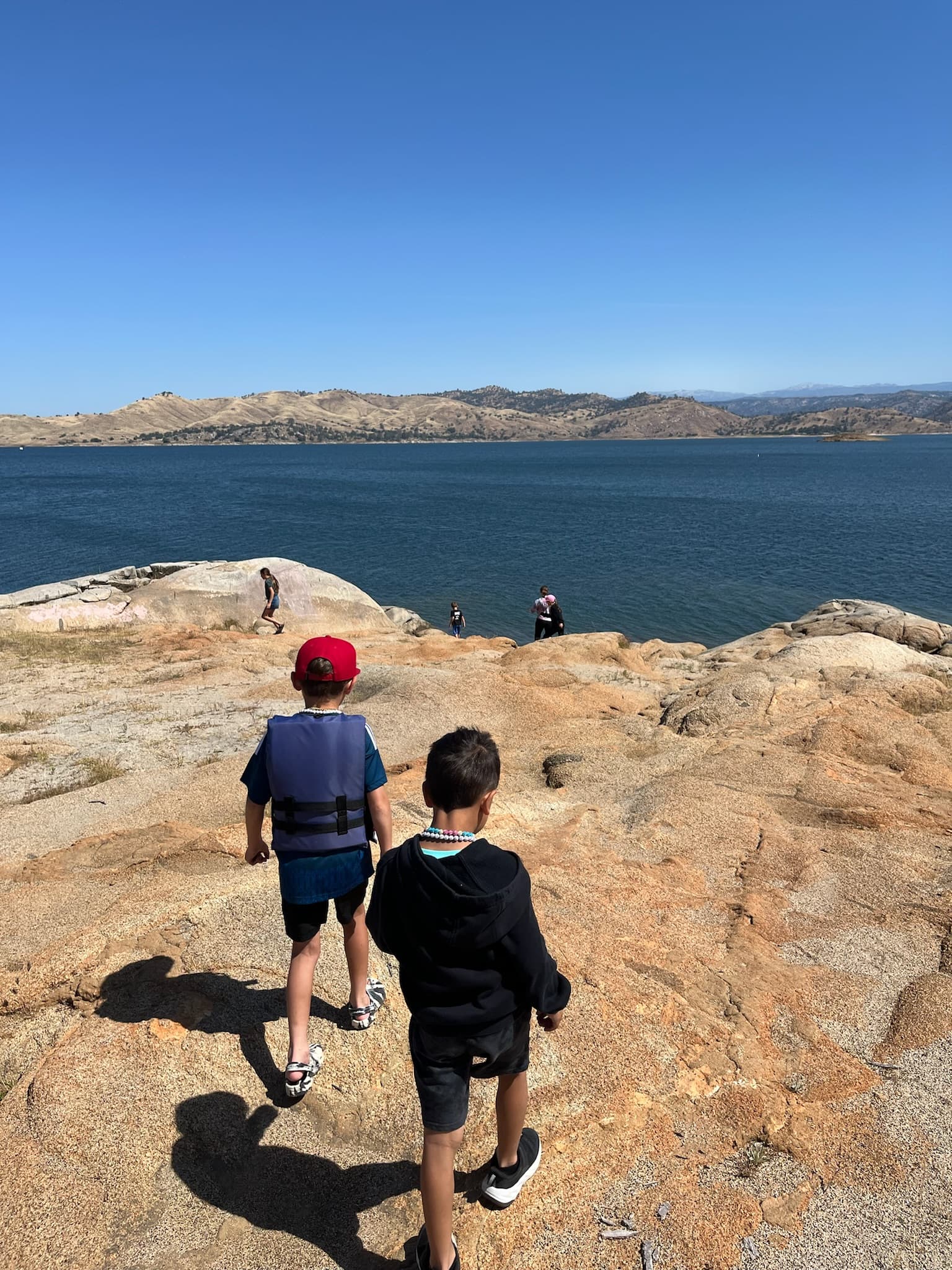 Two students walking together toward the water on a field trip